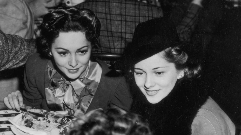 Olivia de Havilland and Joan Fontaine sitting at a dinner together in 1940