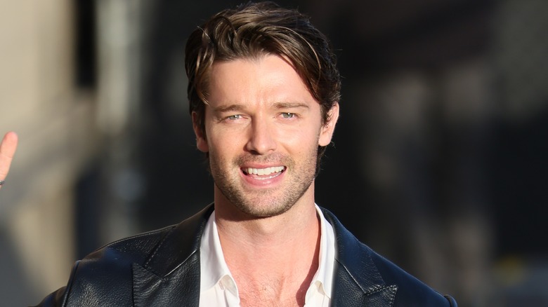 Patrick Schwarzenegger with tousled hair smiling outside