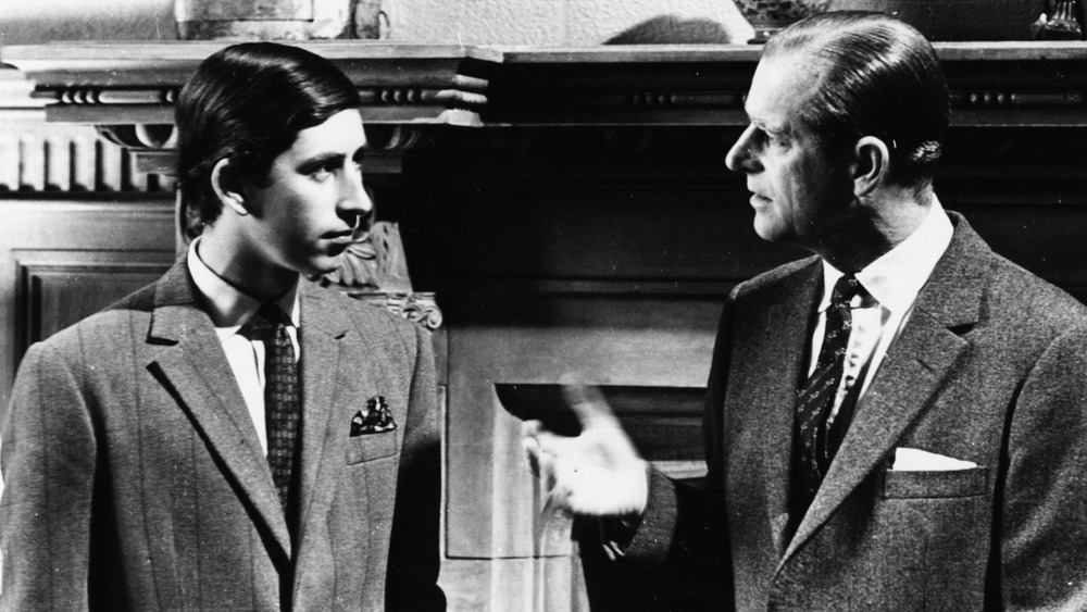 A young Prince Charles and Prince Philip looking at each other sternly