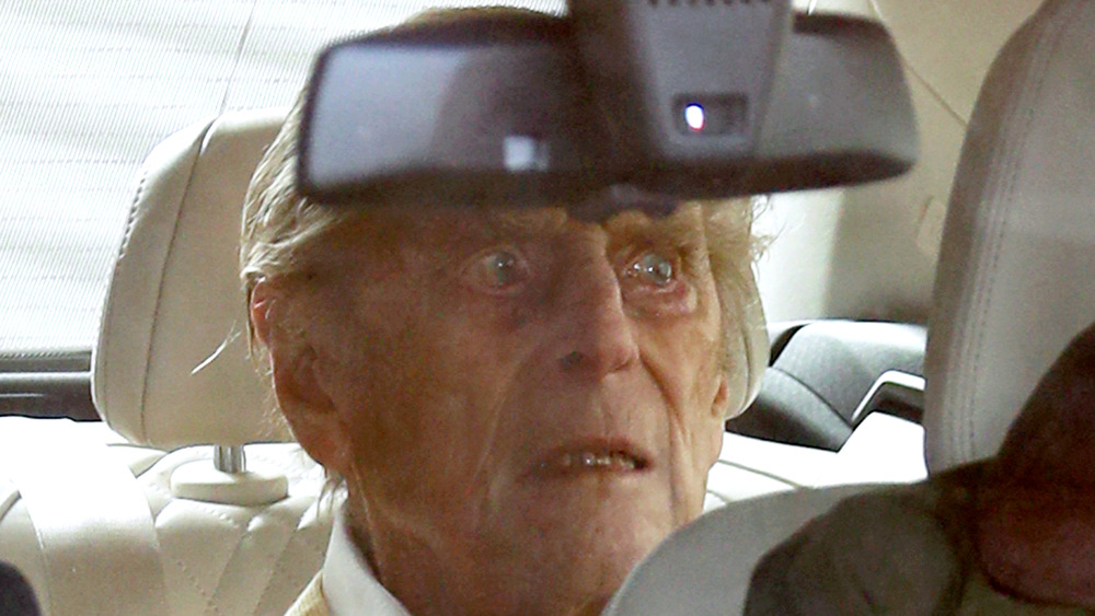 Prince Philip looking grim in the backseat of car