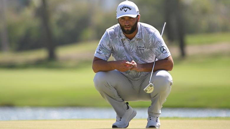 Jon Rahm squatting on golf course