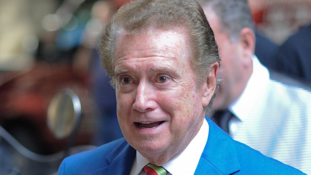 Regis Philbin in a light blue suit and multicolored striped tie, speaking