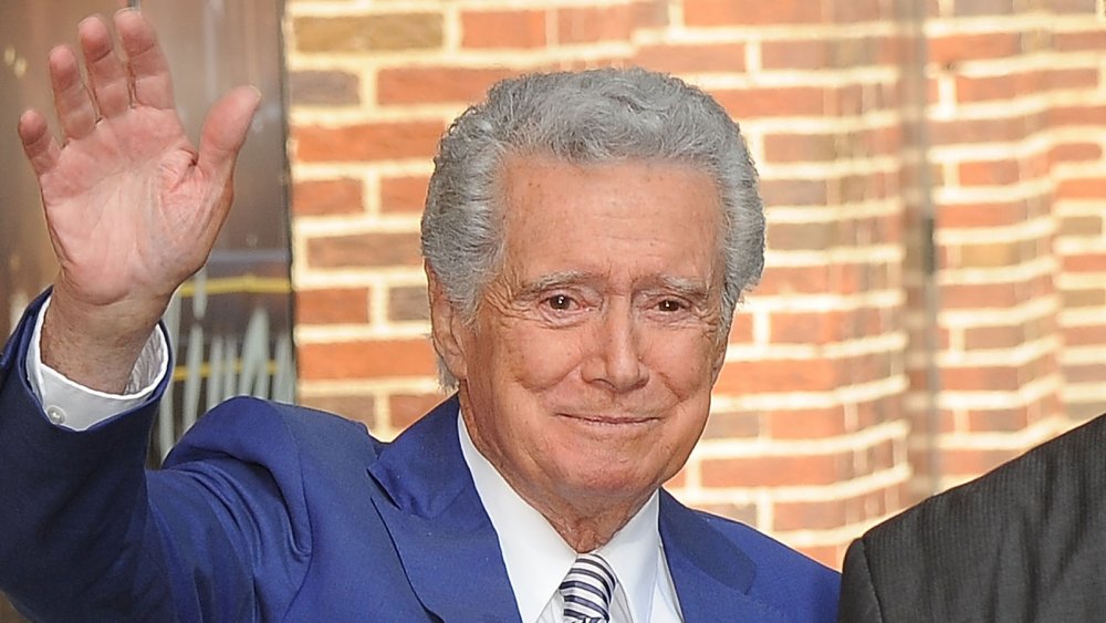 Regis Philbin in a blue suit, waving, with a small smile