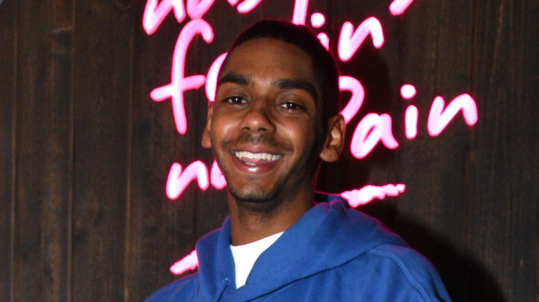 Julian Broadus smiles in blue hoodie