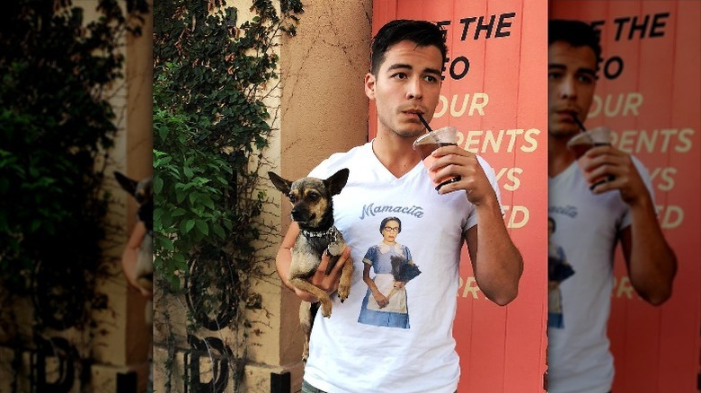 Manolo Gonzalez Vergara holds his dog Mamacita while drinking from straw cup