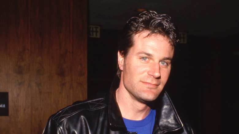 Charles Rocket smiling while wearing a leather jacket and blue shirt