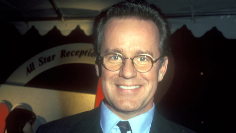 Phil Hartman smiling broadly while wearing a suit