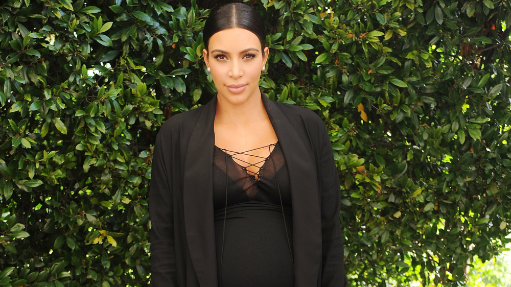 A pregnant Kim Kardashian posing in an all-black outfit