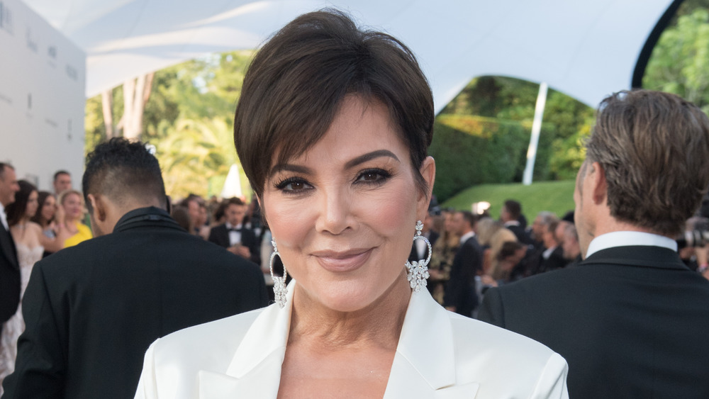 Kris Jenner in a white suit, smirking