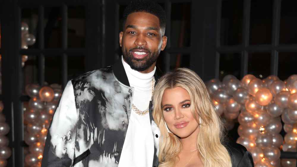 Tristan Thompson and Khloe Kardashian posing arm in arm and smiling