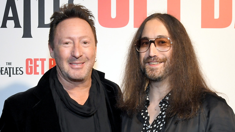 Julian Lennon wearing a black jacket and grey sweater and Sean Ono Lennon wearing a grey jacket and patterned shirt