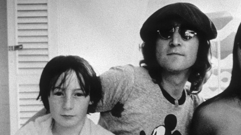 Julian Lennon (left) with a towel around his neck and John Lennon (right) wearing a Mickey Mouse shirt and a pageboy cap