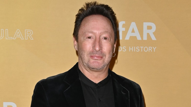 Julian Lennon wearing a black velvet jacket and black high collared shirt