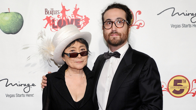 Yoko Ono wearing a black dress and white top hat with son Sean Ono Lennon wearing a black tuxedo and patterned bow tie