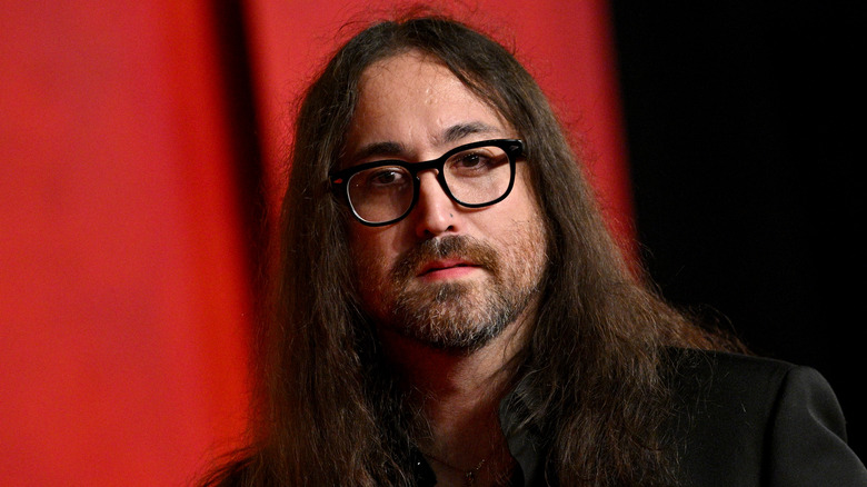 Sean Ono Lennon wearing a black suit and black-framed glasses