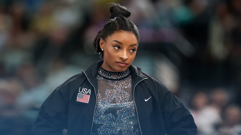 Simone Biles wearing a sparkling leotard and a black USA Nike jacket