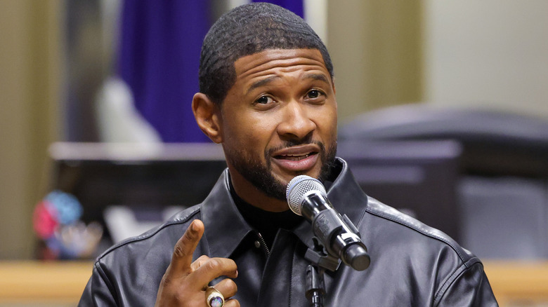 Usher speaking into microphone