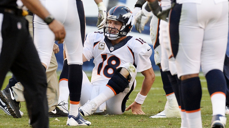 Peyton Manning takes a hit on the field and sits on the ground