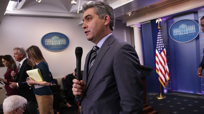 Jim Acosta speaking into a microphone at the White House.