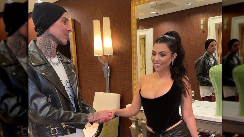 Travis Barker holding Kourtney Kardashian's hand