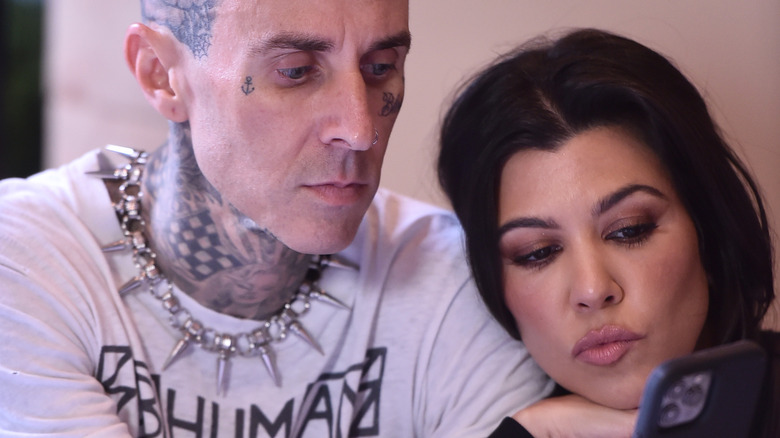 Travis Barker and Kourtney Kardashian looking at phone