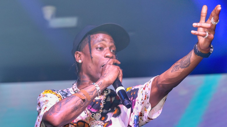 Travis Scott rapping microphone left arm raised