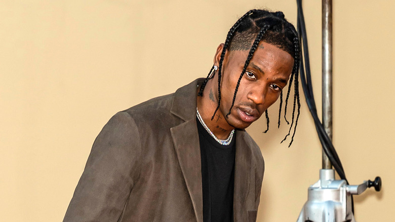 Travis Scott poses in a brown blazer