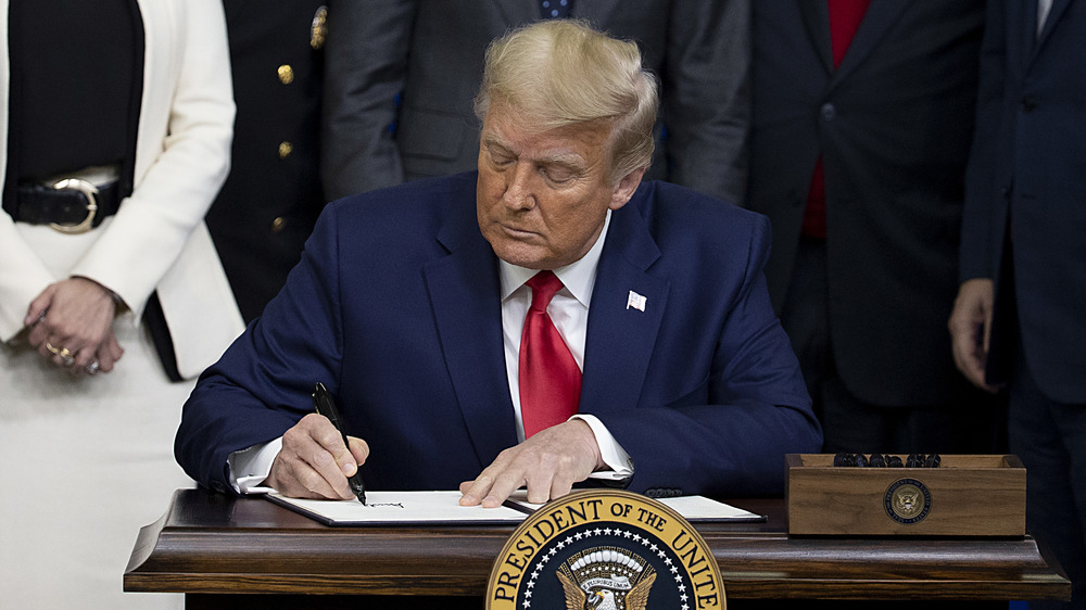 Donald Trump writing at his desk 