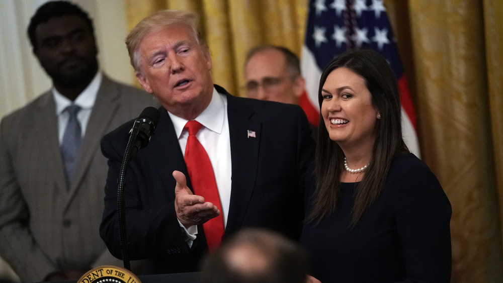 Sarah Huckabee Sanders smiling with Trump