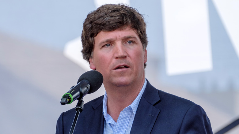 Tucker Carlson speaking into a microphone