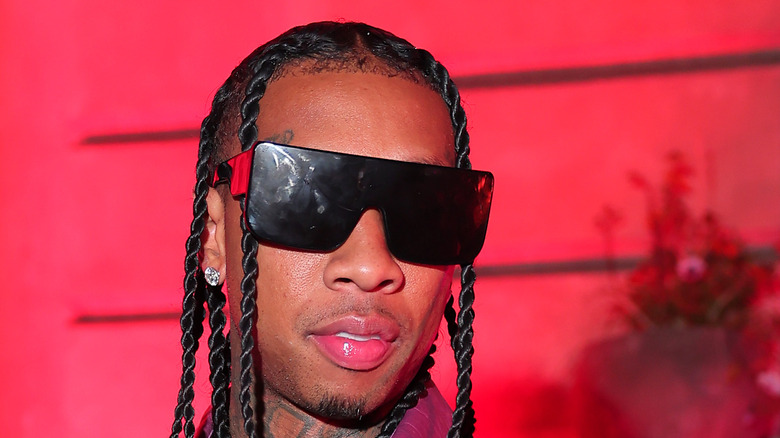 Tyga withi sunglassees against red backdrop