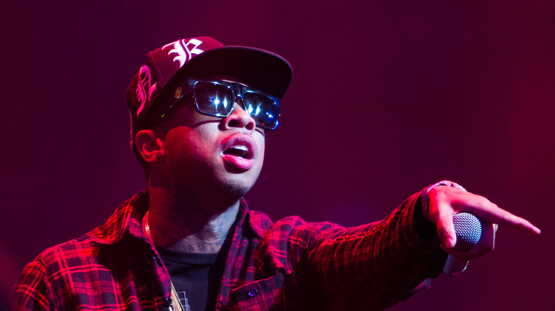 Tyga wearng cap and shades while singing on stage