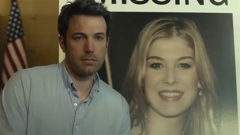 Ben Affleck smiling in front of missing poster