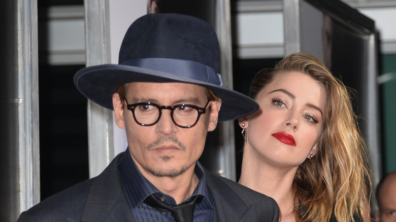 Amber heard walking behind Johnny Depp wearing black hat