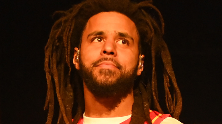 J. Cole on stage wearing a red jersey 