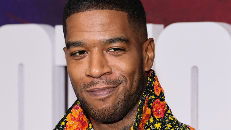 Kid Cudi wearing a floral jacket, smirking