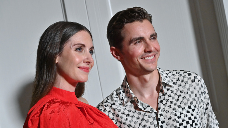 Alison Brie wearing a red top, Dave Franco smiling in a checkered shirt