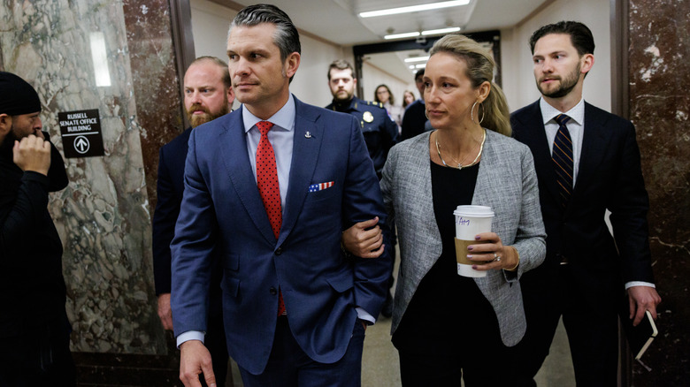 Pete Hegseth and Jennifer Rauchet leaving a meeting with Sen. Tom Cotton in a busy hallway