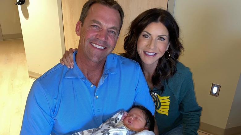 Kristi Noem with her arm around Bryon Noem who is holding their baby