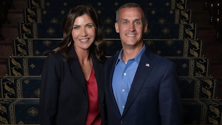 Kristi Noem posing with Corey Lewandowski in front of stairs