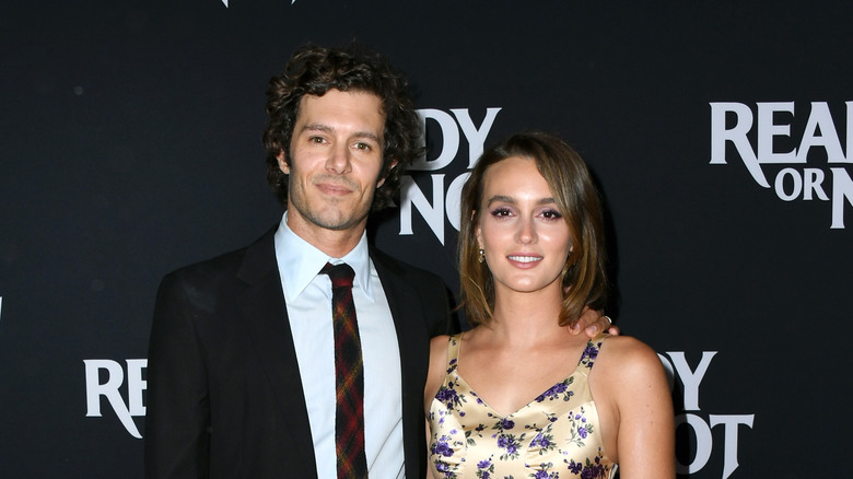 Adam Brody in black suit; Leighton Meester in yellow floral dress