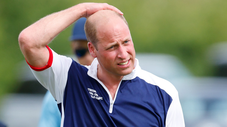 Prince William frowning and touching head