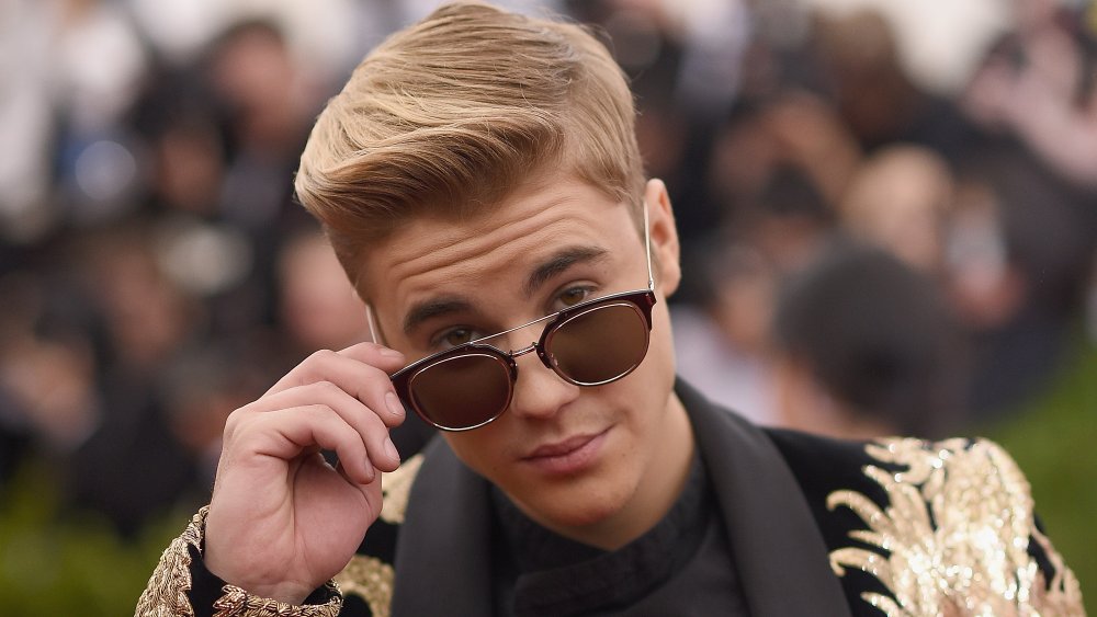 Justin Bieber tilting his head and glancing over a pair of sunglasses