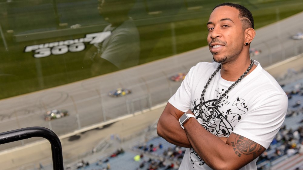 Ludacris smiling with his arms crossed as a Fast and Furious event