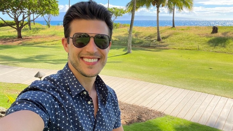 Chris Strandburg smiling in front of palm trees and ocean