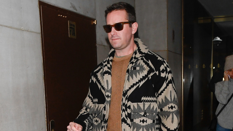 2020 paparazzi photo of Armie Hammer wearing sunglasses and black and beige patterned coat