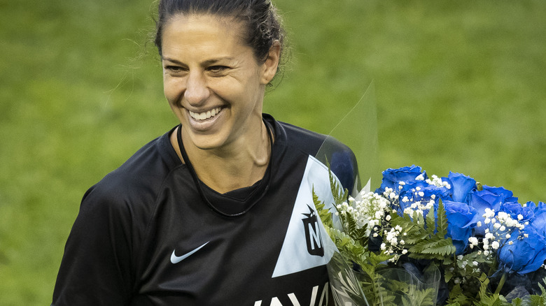 Carli Lloyd smiling with flowers