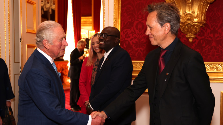 Richard E. Grant shakes hands with Charles