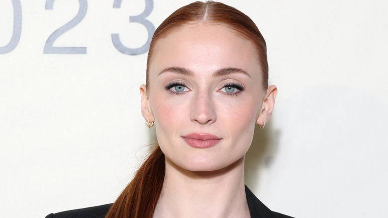 Sophie Turner poses with hard pulled back into a low ponytail