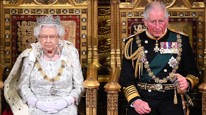 Queen Elizabeth and Prince Charles sitting on thrones